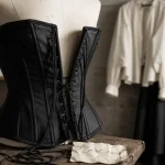Corset femme noir structuré sur mannequin blanc en studio