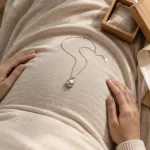 Bola de grossesse, bijoux femme enceinte argentés sur robe beige